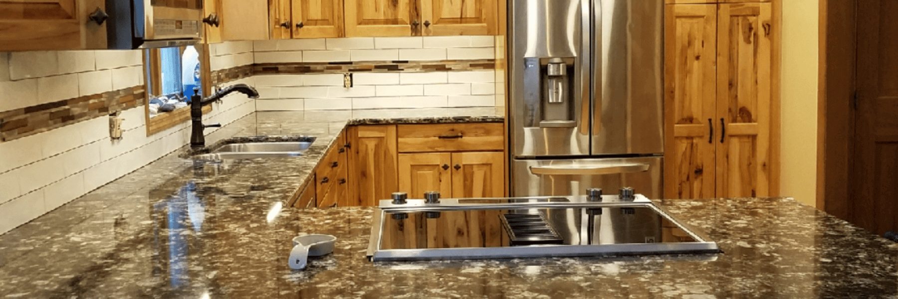 Modern kitchen remodel featuring natural wood cabinets, granite countertops, stainless steel appliances, and tile backsplash with decorative accents